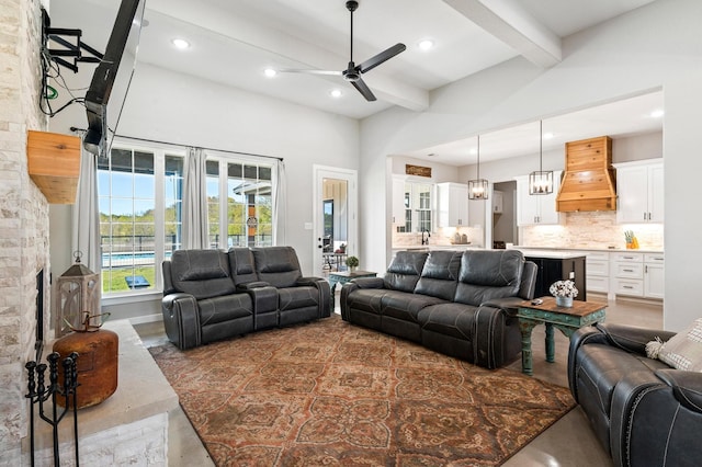 living room with ceiling fan, a towering ceiling, and beamed ceiling