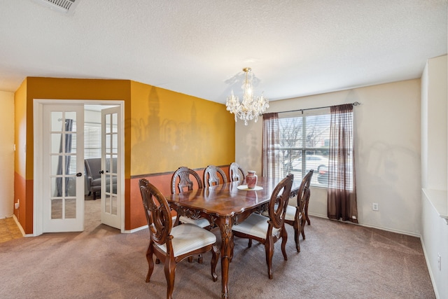 carpeted dining area with a textured ceiling, french doors, and a notable chandelier