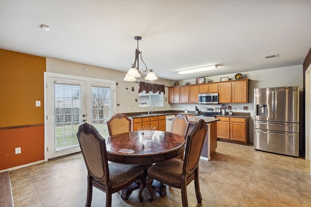 dining space with a textured ceiling, sink, french doors, and a notable chandelier