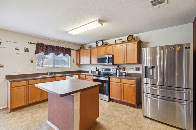 kitchen with a textured ceiling, a center island, sink, and stainless steel appliances