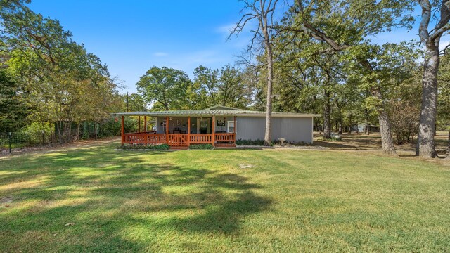 back of house featuring a porch, a yard, and metal roof