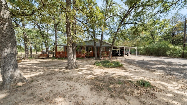 exterior space featuring a carport, dirt driveway, and a wooden deck