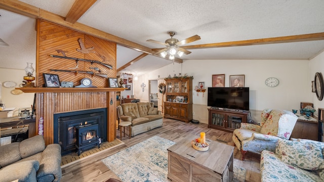 living area with vaulted ceiling with beams, a ceiling fan, a textured ceiling, and wood finished floors