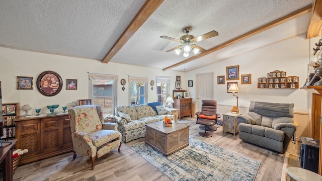living area featuring a textured ceiling, ceiling fan, lofted ceiling with beams, and light wood-style flooring