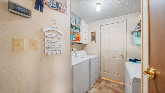 laundry room with cabinet space, a textured ceiling, and washer and clothes dryer