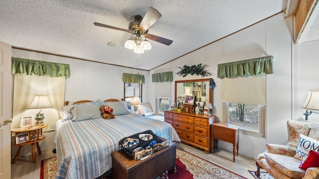 bedroom with lofted ceiling, a textured ceiling, wood finished floors, and multiple windows