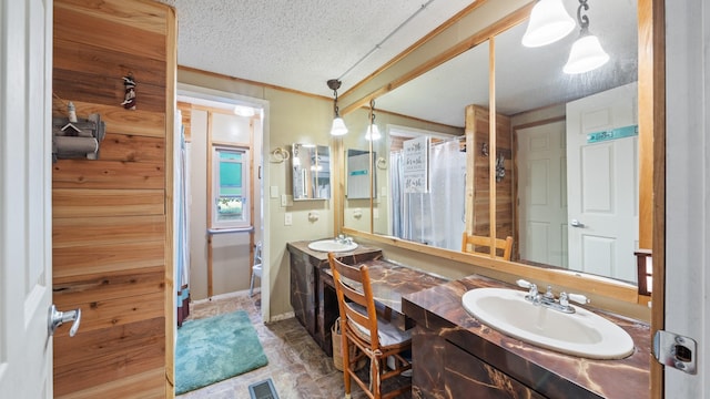 full bath with a textured ceiling, a sink, double vanity, and visible vents
