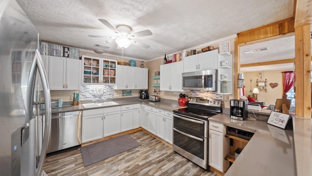 kitchen featuring a textured ceiling, a sink, ceiling fan, stainless steel appliances, and backsplash