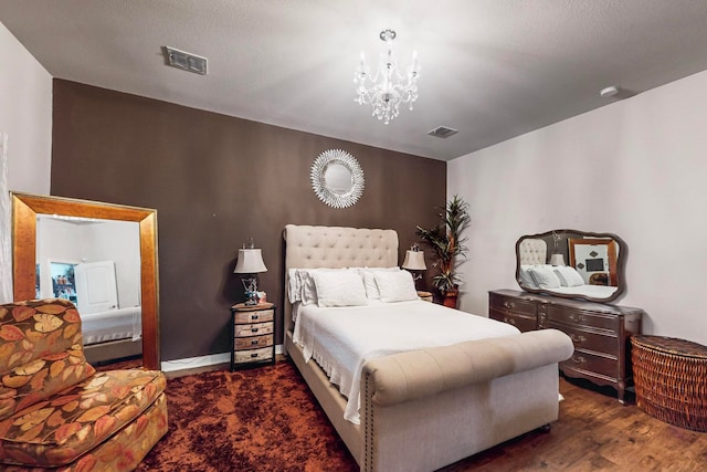 bedroom with dark wood-type flooring, a textured ceiling, and an inviting chandelier