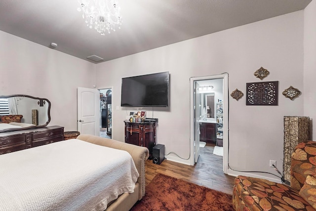 bedroom featuring dark hardwood / wood-style flooring, an inviting chandelier, and ensuite bath