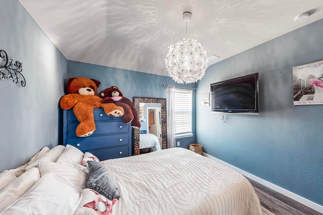 bedroom with a chandelier, hardwood / wood-style floors, and vaulted ceiling