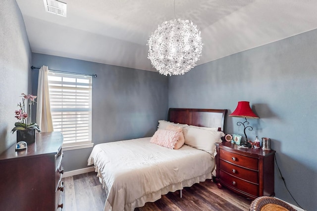 bedroom with dark hardwood / wood-style flooring, lofted ceiling, and a notable chandelier