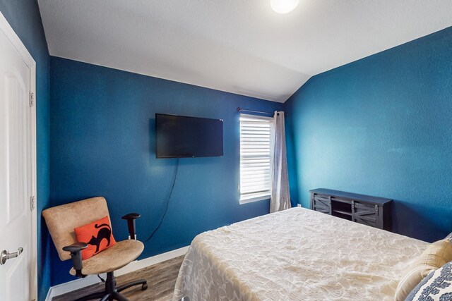 bedroom featuring hardwood / wood-style floors and lofted ceiling