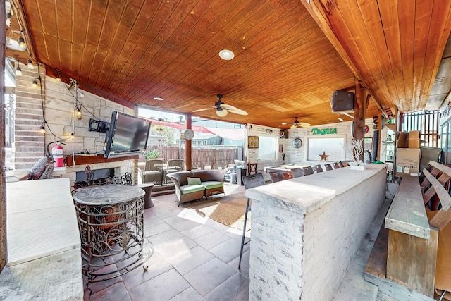 view of patio / terrace with a bar, an outdoor living space, exterior kitchen, and ceiling fan