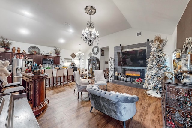 living room featuring a chandelier, light hardwood / wood-style flooring, and vaulted ceiling