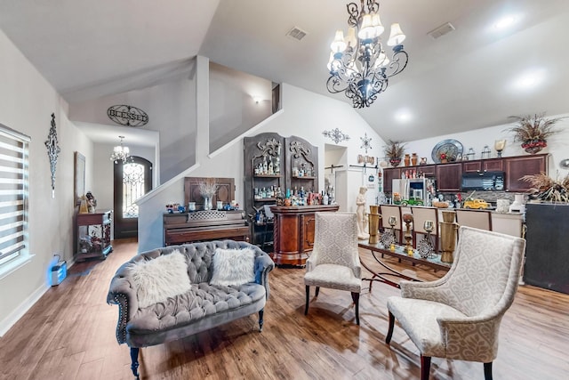 living area featuring high vaulted ceiling, a chandelier, and light hardwood / wood-style flooring