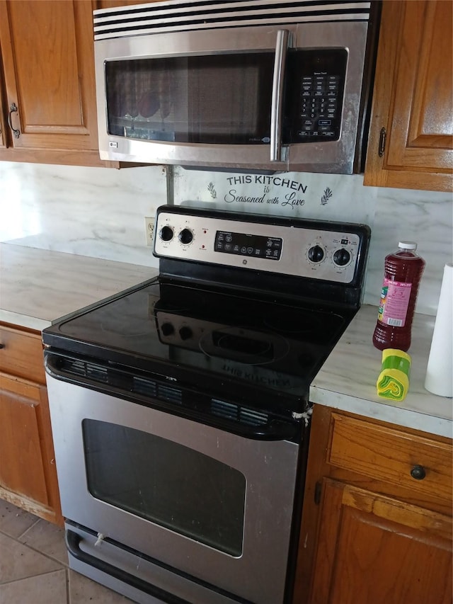 kitchen featuring tasteful backsplash, light tile patterned floors, and stainless steel appliances