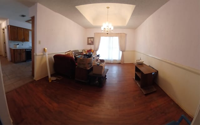 living room with dark hardwood / wood-style flooring, a raised ceiling, and a notable chandelier