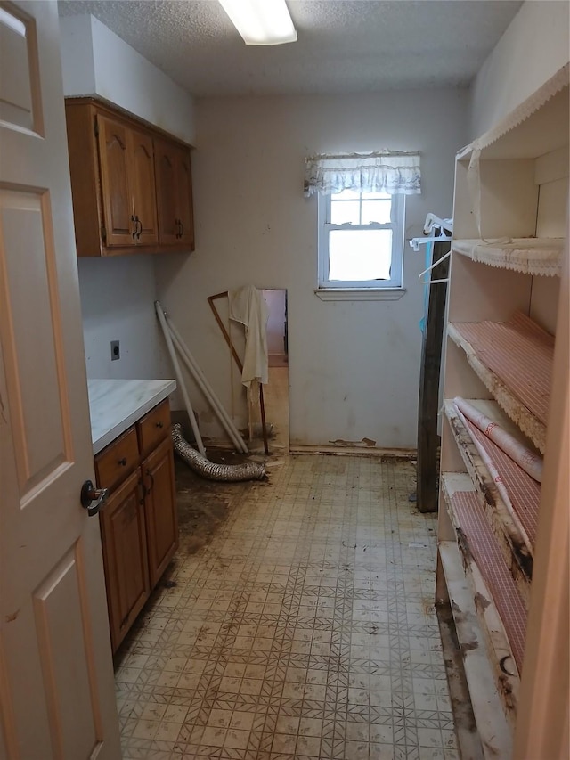 interior space with a textured ceiling, electric dryer hookup, and cabinets