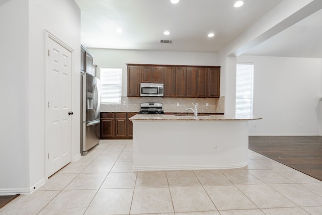 kitchen with light hardwood / wood-style flooring, stainless steel appliances, a center island with sink, and sink