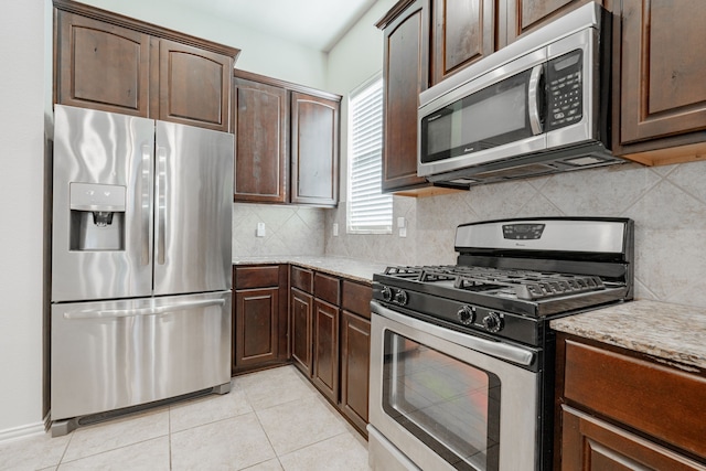 kitchen with light tile patterned floors, tasteful backsplash, light stone counters, dark brown cabinetry, and stainless steel appliances