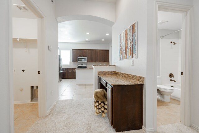 kitchen featuring decorative backsplash, light stone counters, light tile patterned flooring, and appliances with stainless steel finishes