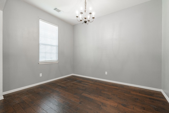 empty room with dark wood-type flooring and a notable chandelier