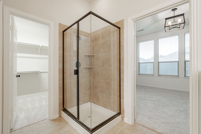 bathroom with tile patterned flooring, a shower with door, and a notable chandelier