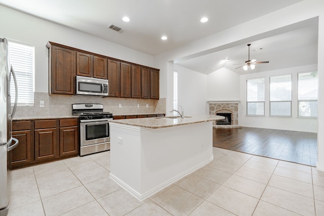 kitchen featuring plenty of natural light, light wood-type flooring, a kitchen island with sink, and appliances with stainless steel finishes