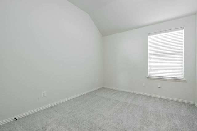 carpeted spare room featuring vaulted ceiling