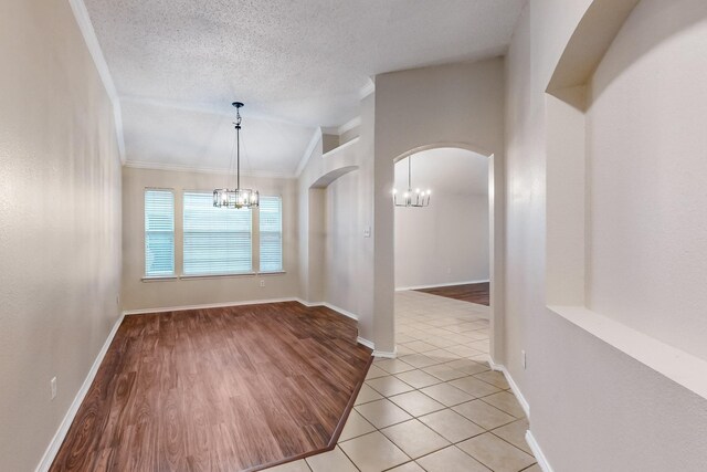 unfurnished living room with a tile fireplace, a textured ceiling, lofted ceiling, light hardwood / wood-style floors, and ceiling fan with notable chandelier