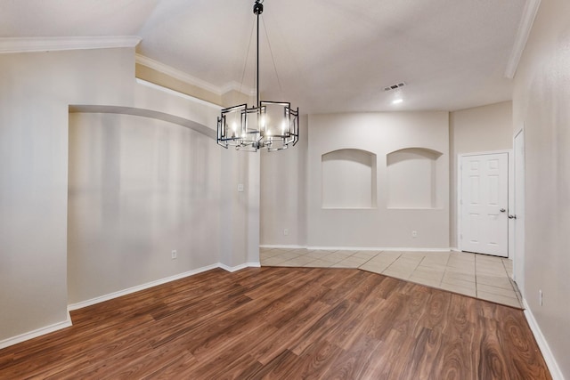 unfurnished dining area with lofted ceiling, crown molding, wood-type flooring, and a chandelier