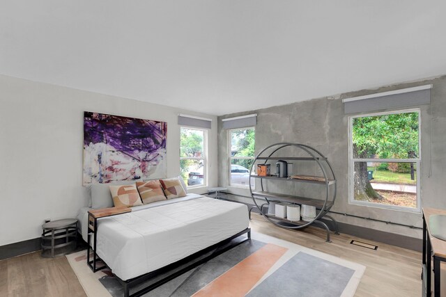 bedroom with light hardwood / wood-style floors and high vaulted ceiling