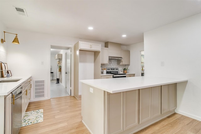 kitchen featuring stainless steel appliances, kitchen peninsula, sink, extractor fan, and light hardwood / wood-style flooring