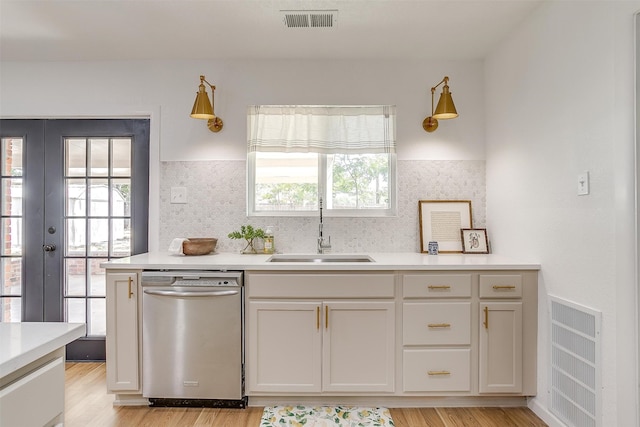 kitchen with dishwasher, light hardwood / wood-style flooring, sink, and french doors