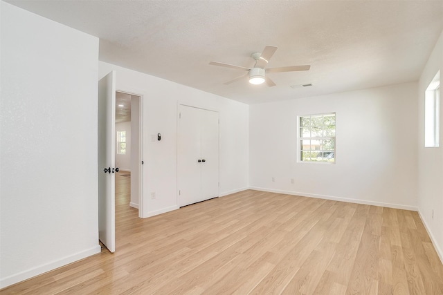 empty room with a textured ceiling, light hardwood / wood-style flooring, and ceiling fan