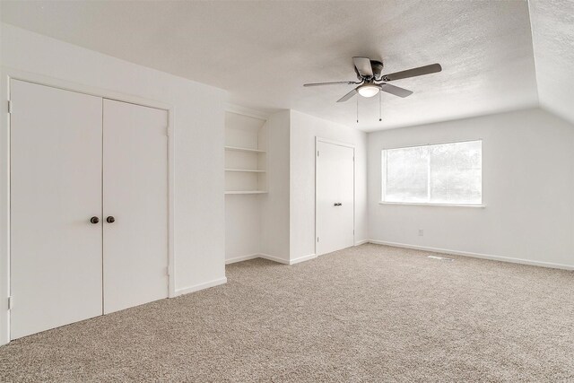 unfurnished bedroom with carpet floors, vaulted ceiling, ceiling fan, and a textured ceiling