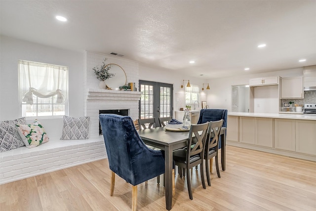 dining space with a brick fireplace and light hardwood / wood-style floors