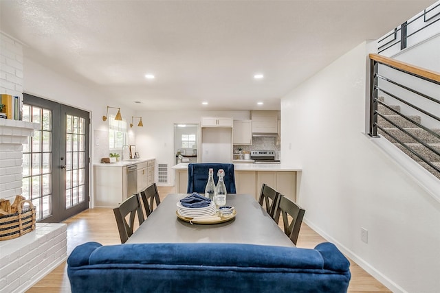 dining space with french doors, sink, and light wood-type flooring