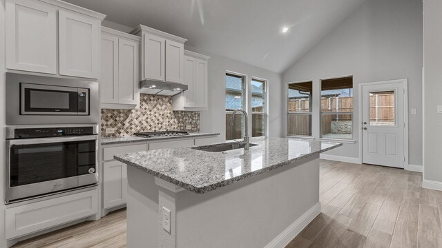 kitchen with stainless steel appliances, white cabinets, a center island with sink, and sink