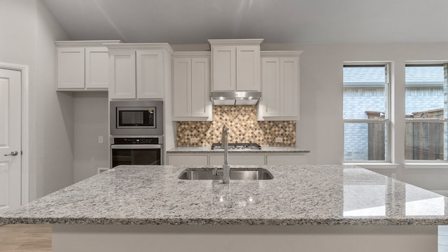 kitchen featuring backsplash, light stone countertops, white cabinetry, and appliances with stainless steel finishes