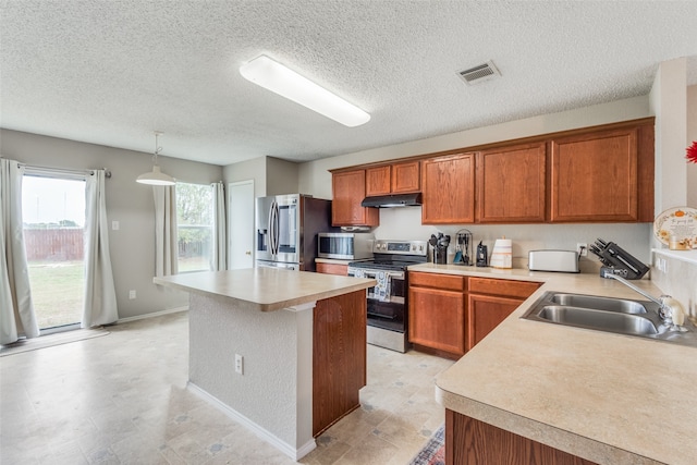 kitchen with sink, hanging light fixtures, a textured ceiling, a kitchen island, and stainless steel appliances