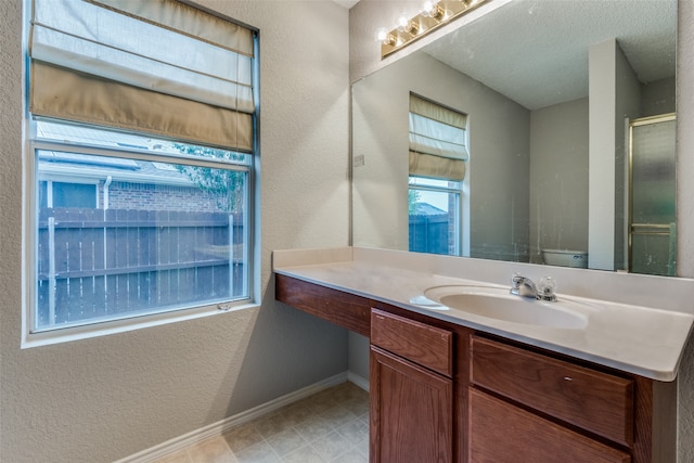 bathroom with vanity, toilet, a shower with door, and a textured ceiling