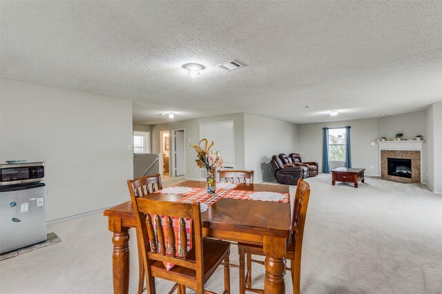 carpeted dining area featuring a fireplace and a textured ceiling