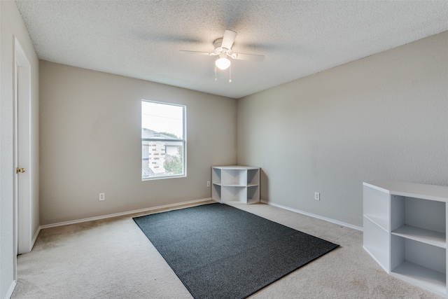 carpeted spare room featuring a textured ceiling and ceiling fan