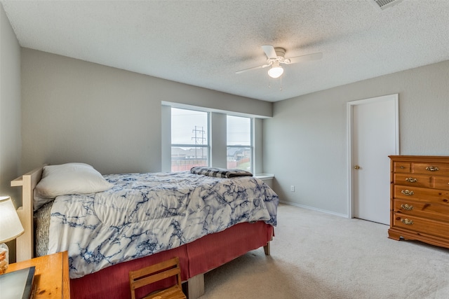 bedroom featuring ceiling fan, light colored carpet, and a textured ceiling