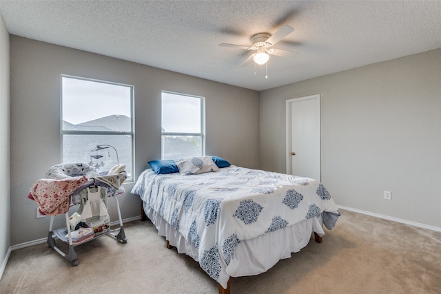 bedroom featuring a textured ceiling, ceiling fan, and light carpet