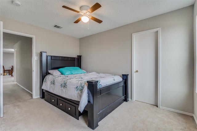 carpeted bedroom with ceiling fan and a textured ceiling