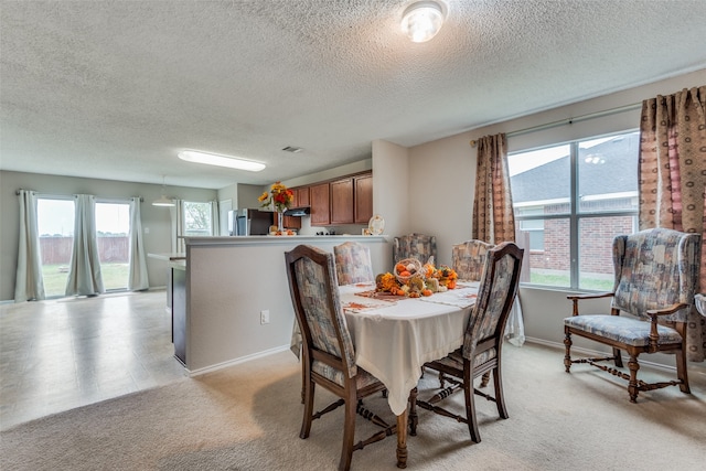 carpeted dining space featuring a textured ceiling