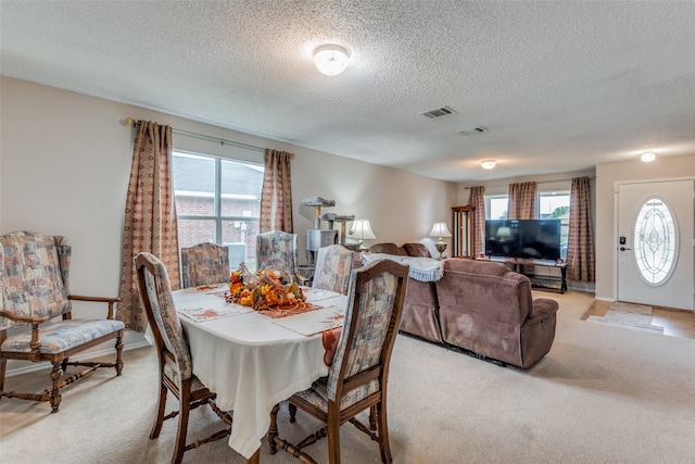 dining space with light carpet and a textured ceiling